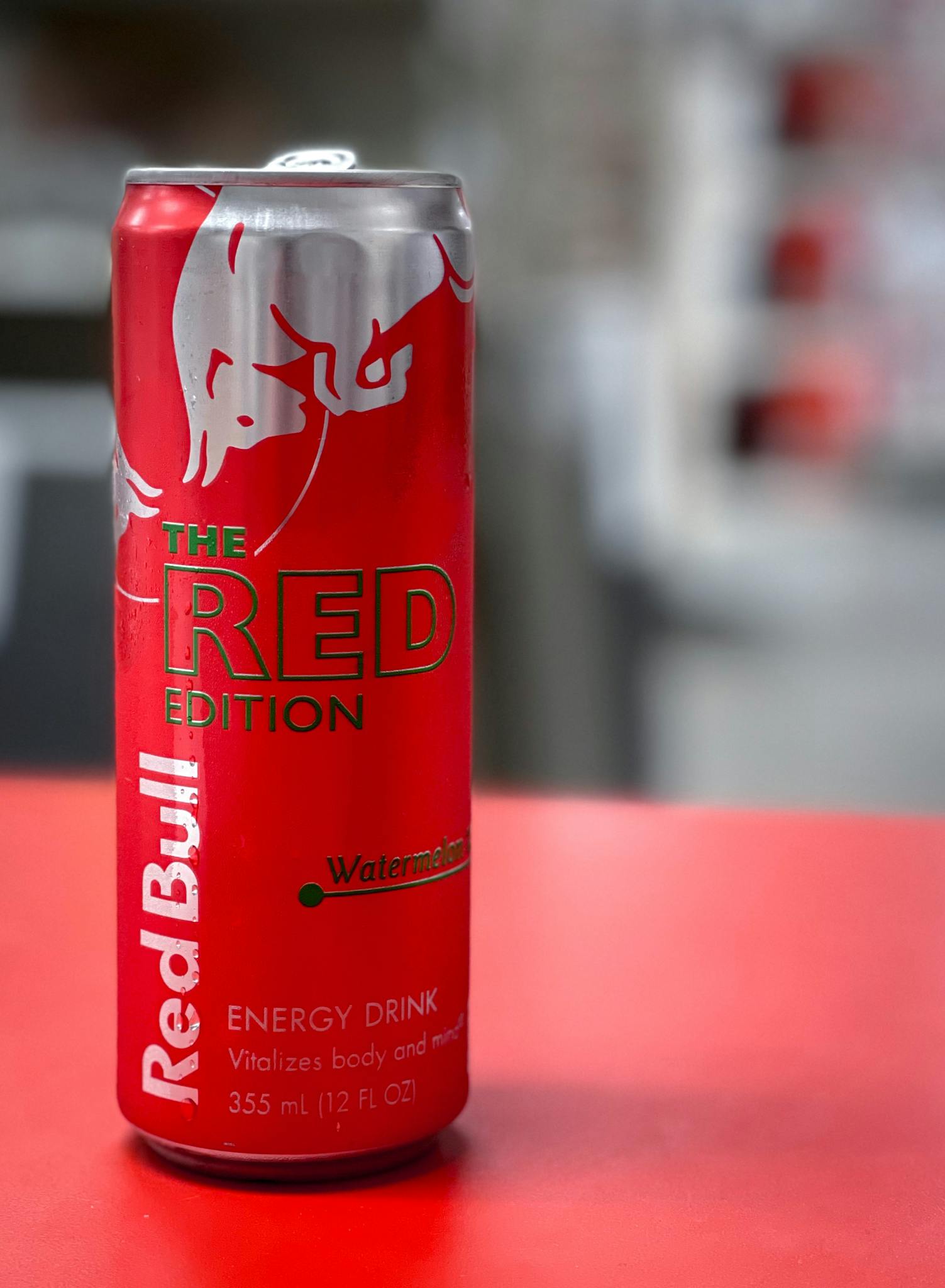 Close-up of Red Bull Watermelon Edition can on red surface.